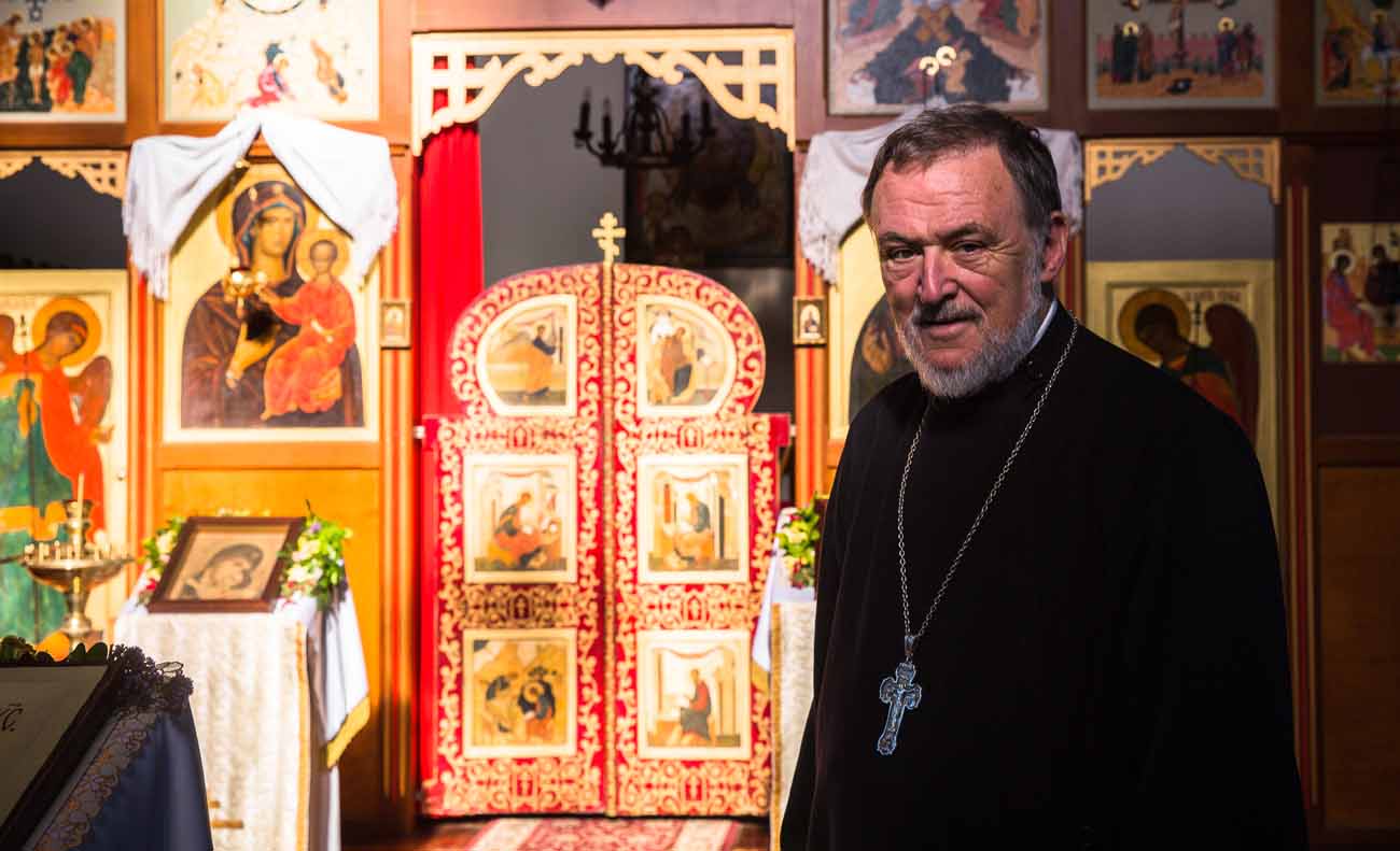 Father Lawrence Cross stands in front of the iconostasis in the Russian Catholic Church of St. Nicholas