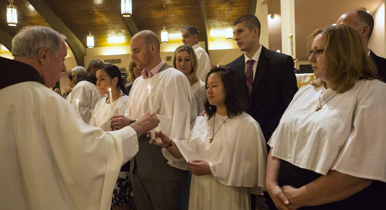 The newly baptized receive their baptismal candles during the Easter Vigil April 16 at St. Francis of Assisi Church in Triangle Va. Thousands of new Catholics joined the Catholic Church during the Easter Vigil at churches around the U.S. (CNS photo/Octavio Duran)