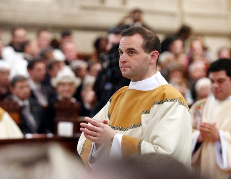 Transitional Deacon Eric Banecker wears the dalmatic, the outer liturgical vestment of a deacon, for the first time as he prays during the ordination rite.