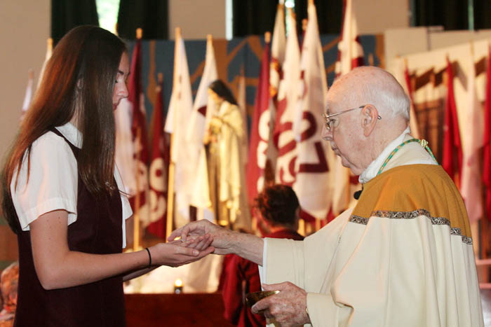 senior Meagan Gormley receives communion from Bishop Maginnis