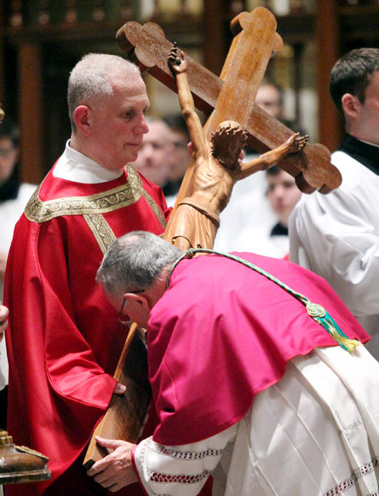 Transitional Deacon James Cordosi holds the cross as Archbishop Charles Chaput venerates