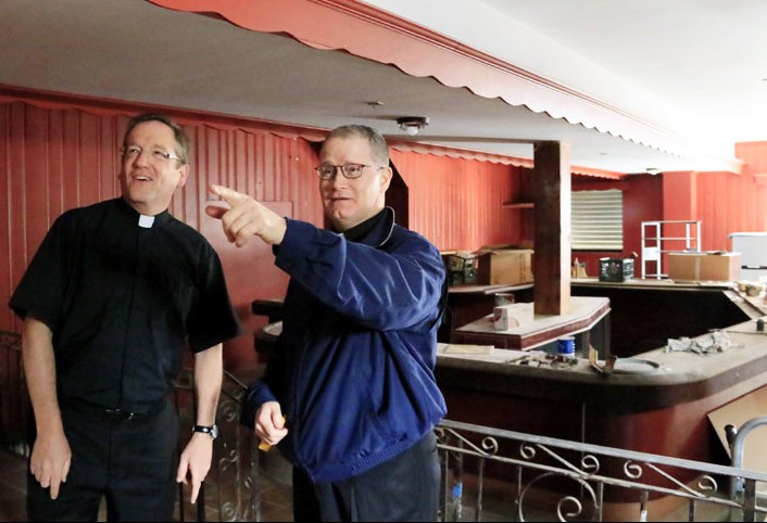 Fathers Murphy (left) and Devlin discuss possible ideas for a chapel at their storefront outreach, once it's renovated, after it officially opens June 15. (Sarah Webb)