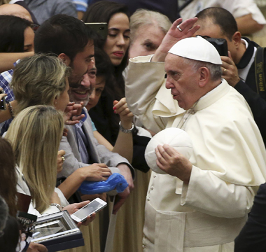 Pope Francis has fun exchanging his zucchetto, or skull cap, with a pilgrim during his weekly audience in Paul VI hall at the Vatican Aug. 19. (CNS photo/Alessandro Bianchi, Reuters)