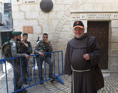 Brother Mark McPherson of Los Angeles walks by the fifth station of the cross on the Via Dolorosa in Jerusalem's Old City Oct. 18, as Israeli border police stand guard near a site where several recent stabbings have taken place. (CNS photo/Debbie Hill) 