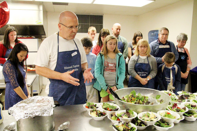 Deacon David Kubczak leads the group in prayer before serving dinner to those in need.