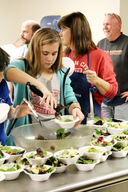 Elizabeth Beehler dishes out salad while feeding those in need.