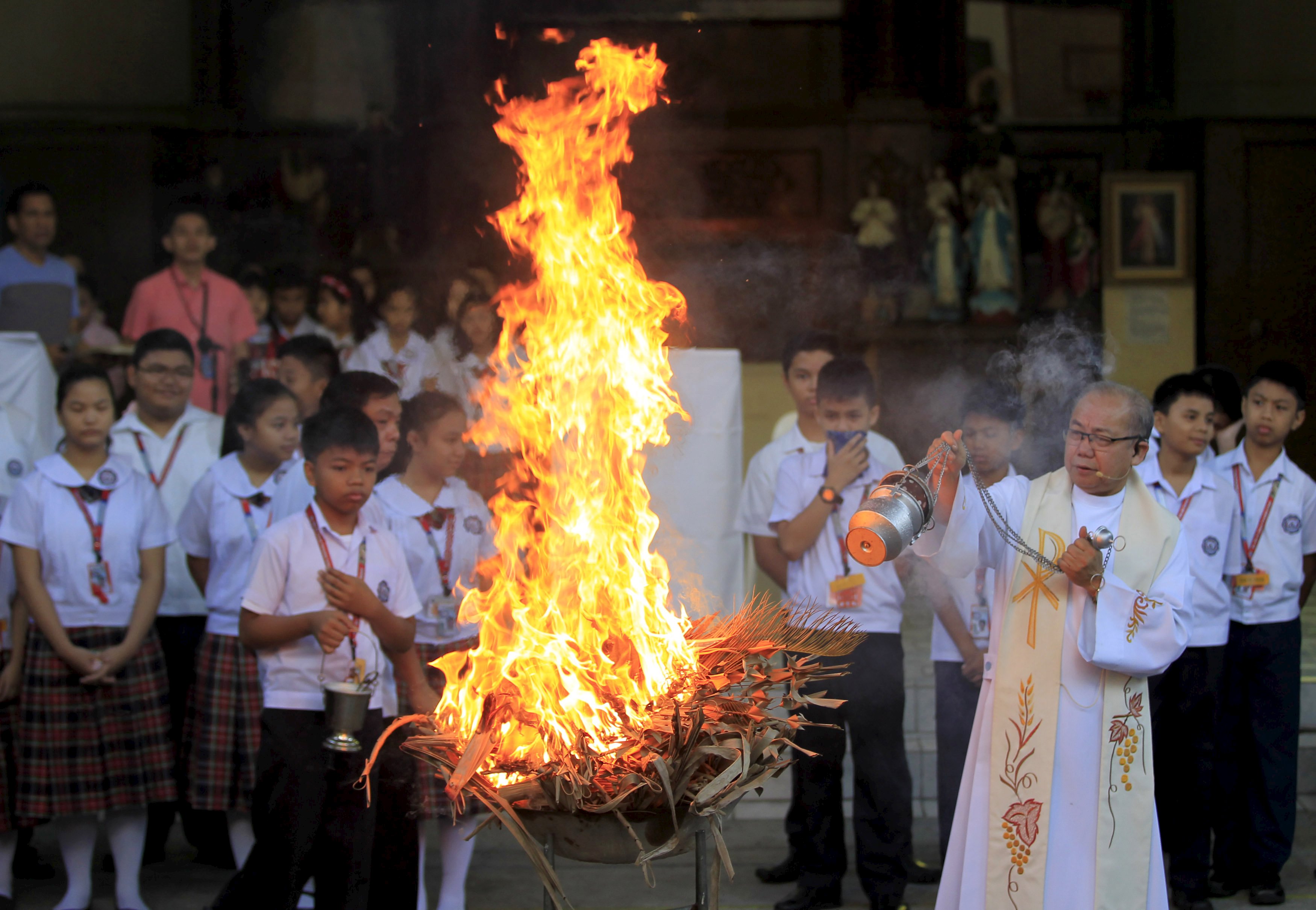 A priest blesses burning dried palm leaves Feb. 9 inside a Catholic school in Manila, Philippines. Ashes from the fire were to be used in Ash Wednesday services the next day, the first day of the penitential season of Lent. (CNS photo/Romeo Ranoco, Reuters)