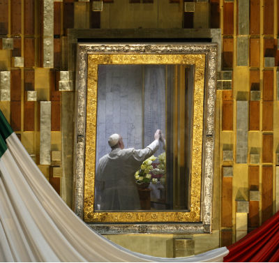 Pope Francis touches the original image of Our Lady of Guadalupe after celebrating Mass in the Basilica of Our Lady of Guadalupe in Mexico City Feb. 13. The Marian image was rotated for the pope to pray in the "camarin" ("little room") behind the main altar. (CNS photo/Paul Haring)