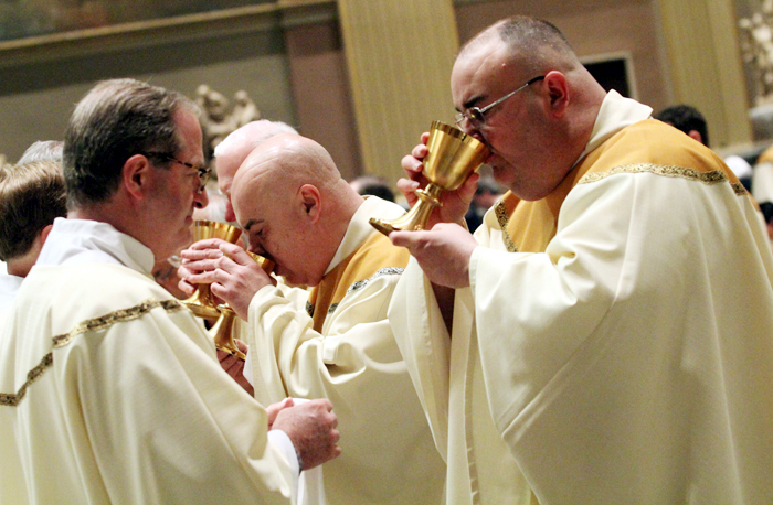 Fathers Michael Olivere and John Babowitch receive the blood of Christ.