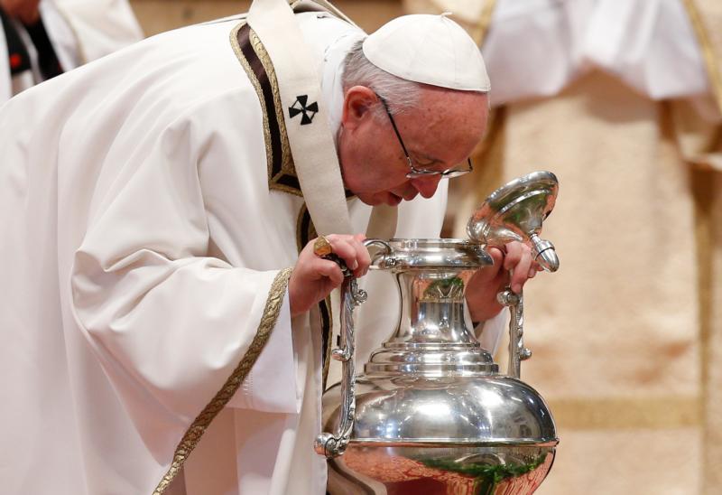 Pope Francis breathes over chrism oil, a gesture symbolizing the infusion of the Holy Spirit, during the Holy Thursday chrism Mass in St. Peter's Basilica at the Vatican March 24. (CNS photo/Paul Haring) See POPE-CHRISM-MASS March 24, 2016.