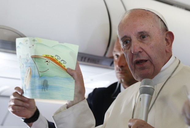 Pope Francis shows a drawing given by a child as he answers questions from journalists aboard his flight from the Greek island of Lesbos to Rome April 16, 2016. The drawing was given by a child at the Moria refugee camp in Lesbos where the pope met 250 people. The pope concluded his visit by bringing 12 refugees from Greece to Italy with him. (CNS photo/Paul Haring)