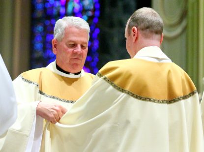 Father Paul Kennedy helps Father Matthew Windle don the vestments of a priest for the first time.