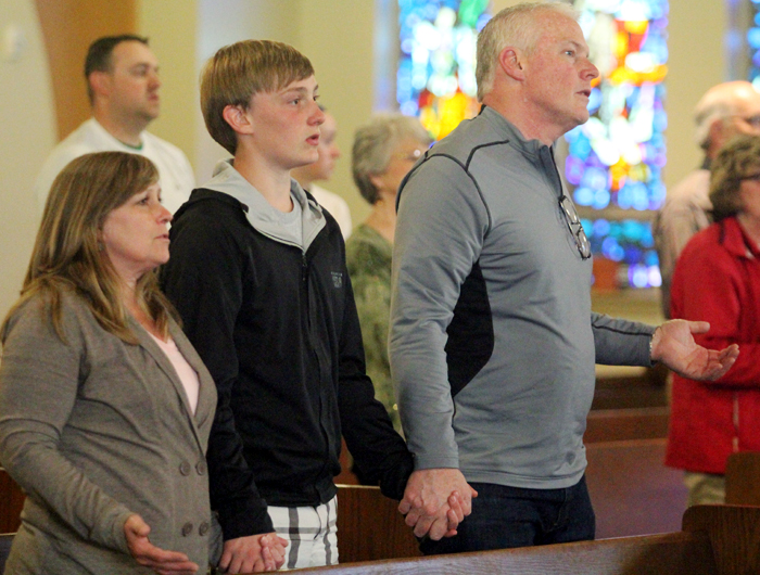 Stephanie, Adam and Keith Brown hold hands to pray together.