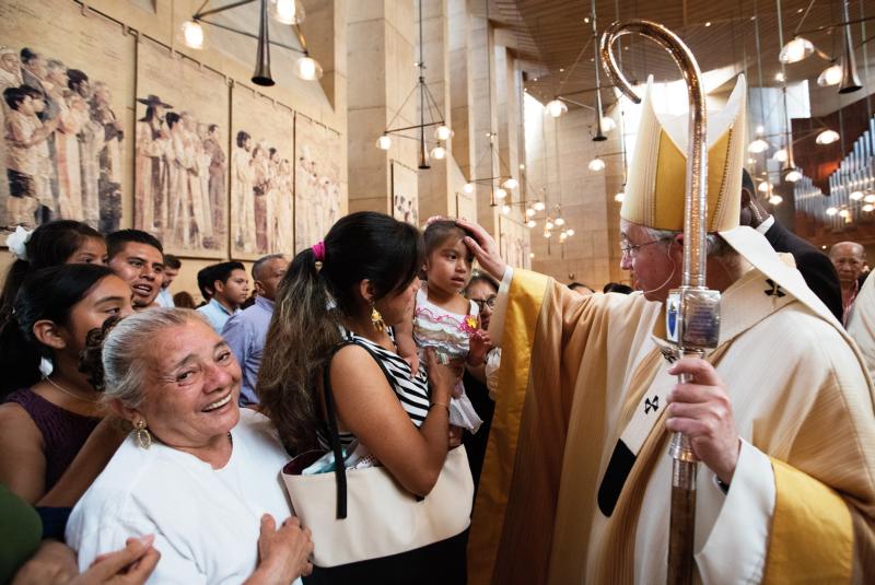 Archbishop Jose H. Gomez of Los Angeles blesses a girl during a special Mass celebrated July 17 in recognition of all immigrants at the Cathedral of Our Lady of the Angels in Los Angeles. (CNS photo/Victor Aleman, Vida Nueva)