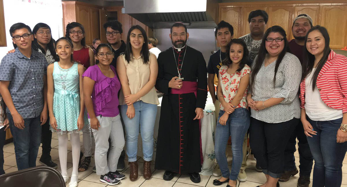 Bishop Daniel E. Flores of Brownsville, Texas, poses for a photo July 10 with youth volunteers who serve and prepare meals for unaccompanied children from Central America. (CNS photo/Rose Ybarra, The Valley Catholic)