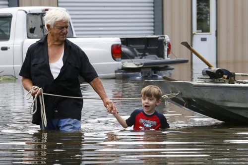 Richard Rossi and his 4-year-old great-grandson Justice wade through water Aug. 15 after their home flooded in St. Amant, La. (CNS photo/Jonathan Bachman, Reuters) 