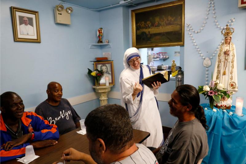 Sister Mary Marta, a member of the Missionaries of Charity, chats with guests after reading from the Bible in a soup kitchen run by her order in an apartment building in the South Bronx section of New York Aug. 24. (CNS photo/Gregory A. Shemitz)