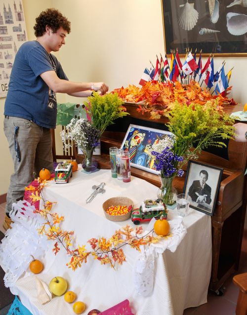 Ryan Pallas, a Spanish-language student at Nazareth College, helps decorate a Day of the Dead altar at the college in Pittsford, N.Y., Nov. 2. The Mexican tradition is often observed by families who build altars in their homes and decorate them with flowers, food and sugar skulls in honor of deceased loved ones. (CNS photo/Mike Crupi, Catholic Courier)