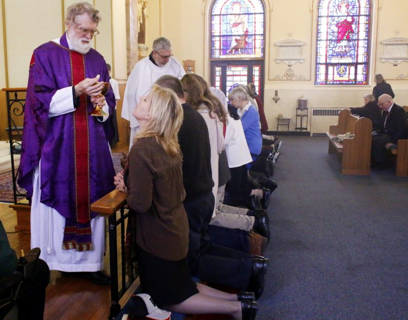 Father David Ousley distributes holy Communion at the altar rail at St. John the Baptist Church for his congregation of former Anglicans and Episcopalians who are in communion with the Catholic Church under a personal ordinariate establish by the pope in 2012. (Photo by Sarah Webb)