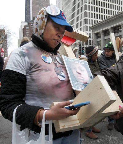 Tykina Watts carries a photo of her daughter and a cross with her daughter's name, Tykina Ali, during a Dec. 31 march against gun violence in downtown Chicago. (CNS photo/Karen Callaway, Catholic New World) 