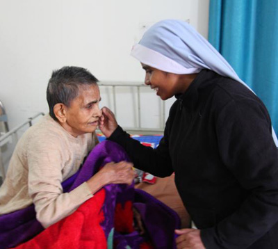A religious sister is seen comforting a sick woman in 2016 at Snehadam Old Age Home in Gurgaon, India. (CNS photo/courtesy John E. Kozar, CNEWA) 
