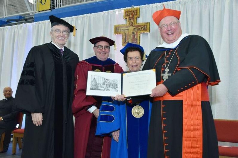 Cardinal Timothy Dolan of New York joyfully receives his honorary degree from James Delaney (left), chairperson of the Neumann University board of trustees; Lawrence DiPaolo (second from left), vice president for academic affairs; and Rosalie Mirenda, university president.