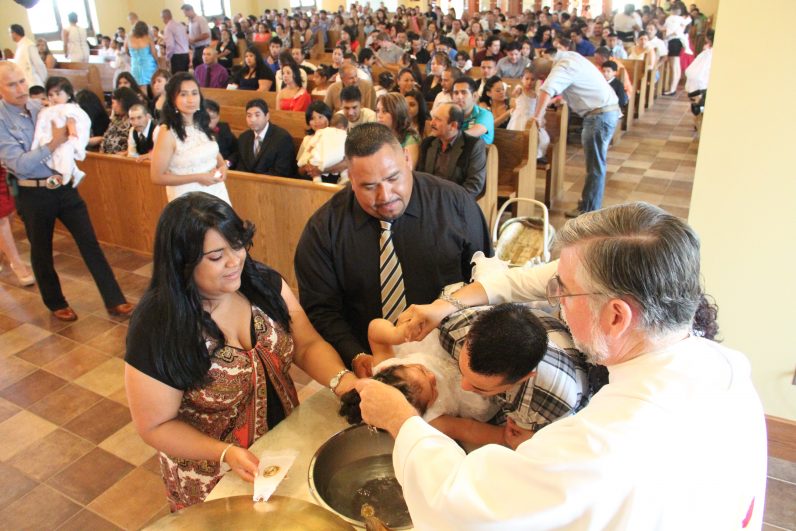 Msgr. Francis Depman (bottom) pastor of St. Rocco Parish in Avondale, baptizes a child in the southern Chester County church. The Hispanic national parish is booming, with its 508 baptisms last year only one indicator. Most of the parishioners are recent immigrants, many of whom are without legal documentation. (Sarah Webb)