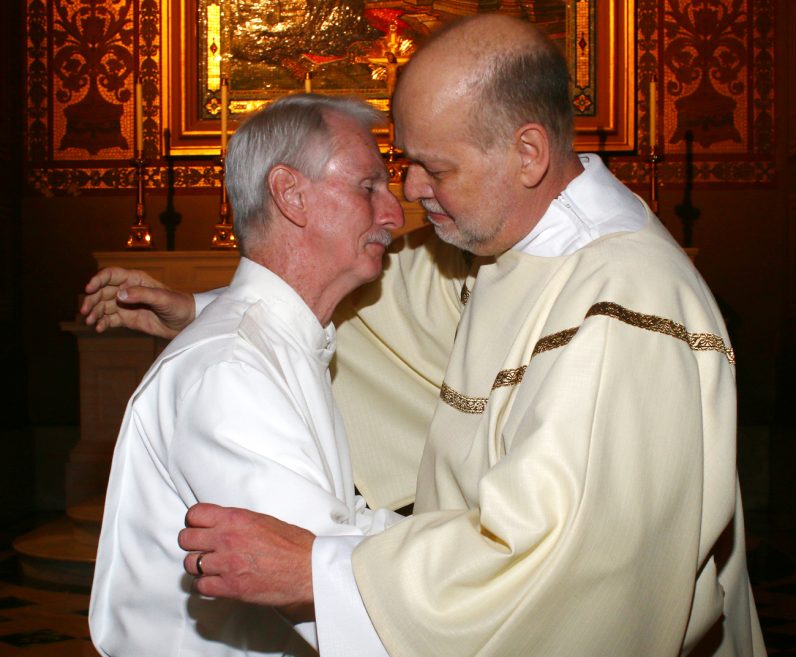 Deacon Jack Pfeifer, right, reaches out to his friend Joe Murphy, who proclaimed a reading during the permanent deacon ordination Mass June 10 in the Cathedral Basilica of SS. Peter and Paul. (Sarah Webb)