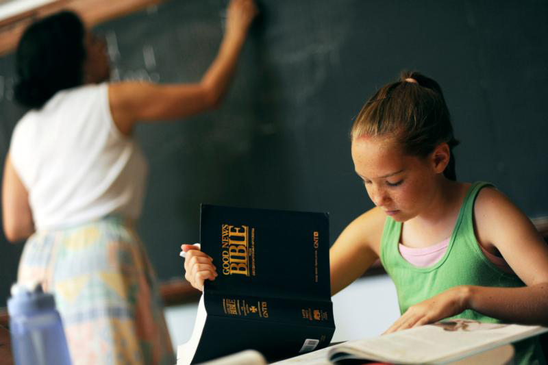 A student follows along with her study Bible during a 2010 summer religious education class at St. Charles Borromeo Parish in Greece, N.Y. Churches need to make sure that they do not inadvertently give the message that nothing is happening during summer months. Weekly podcasts, small faith groups, summer film series and book discussions are some ways to keep "faith thoughts" in the minds of parishioners throughout the vacation season. (CNS photo/Mike Crupi, Catholic Courier) 