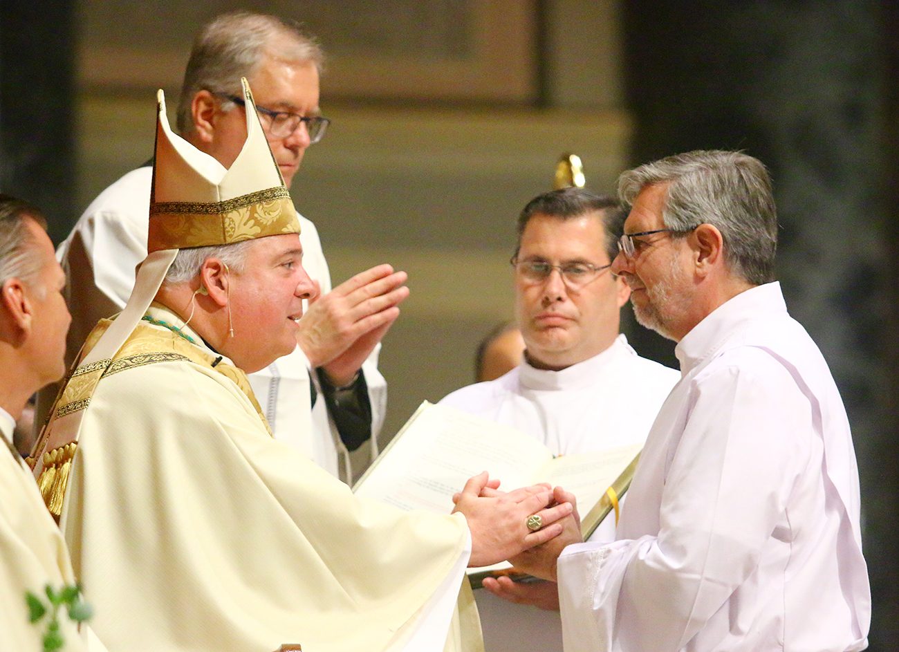 Deacon Franz N. Fruehwald right) makes the promise of the elect to Archbishop Nelson Perez during the diaconate ordination Mass June 13.
