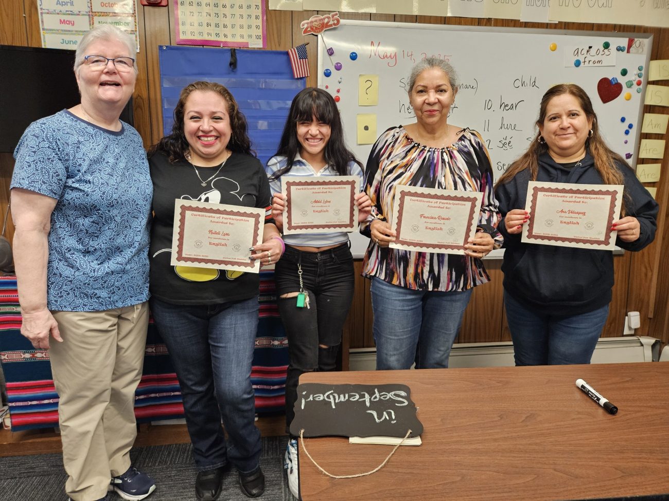 Group of SSJ Welcome Center students smiling and holding English course certificates on the last day of class, May 14, 2025.