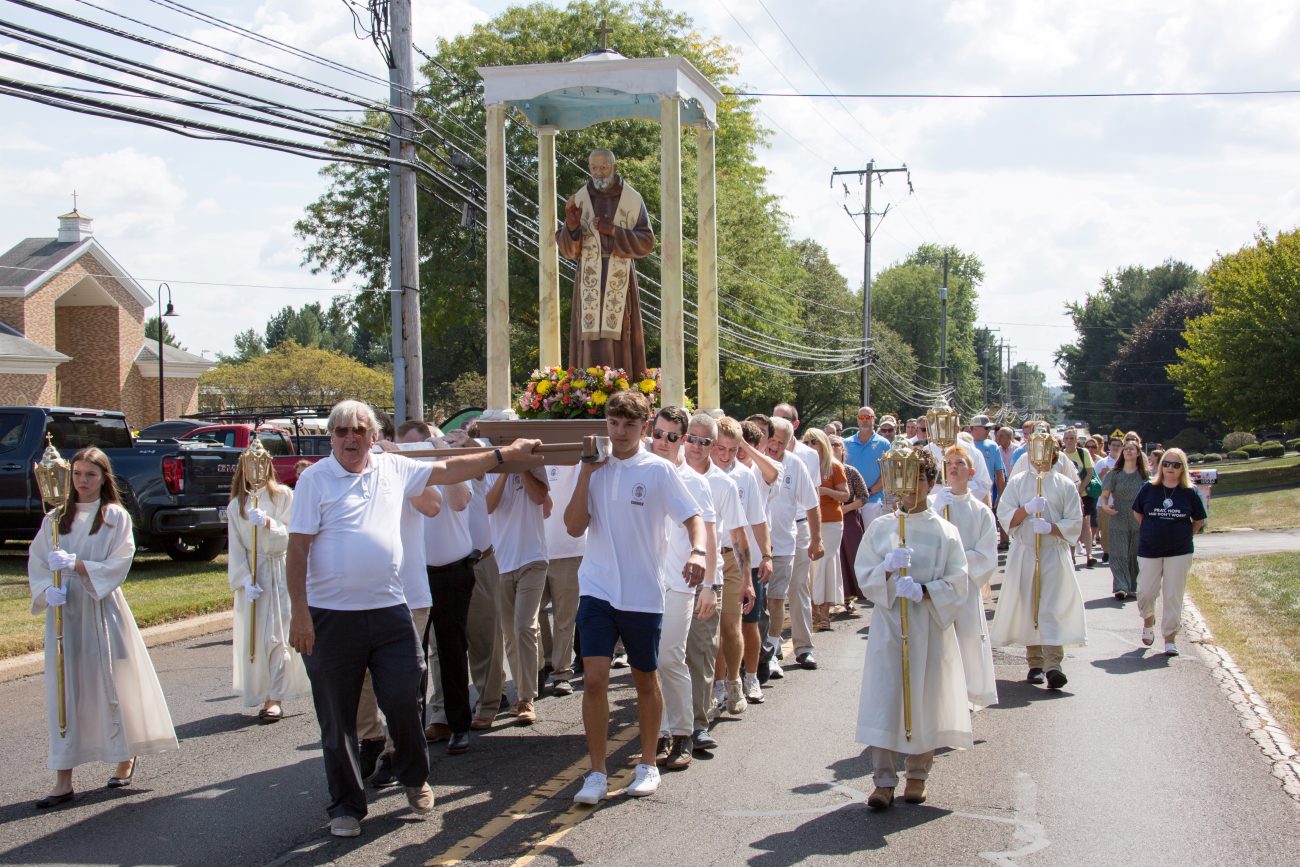 Parishioners walk outdoors carrying a statue of St. Pio of Pietrelcina on a platform during the 2024 Padre Pio Festival at St. Bede the Venerable Parish in Holland, Pa.